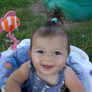 A giggling baby enjoying outdoor time in a bouncer