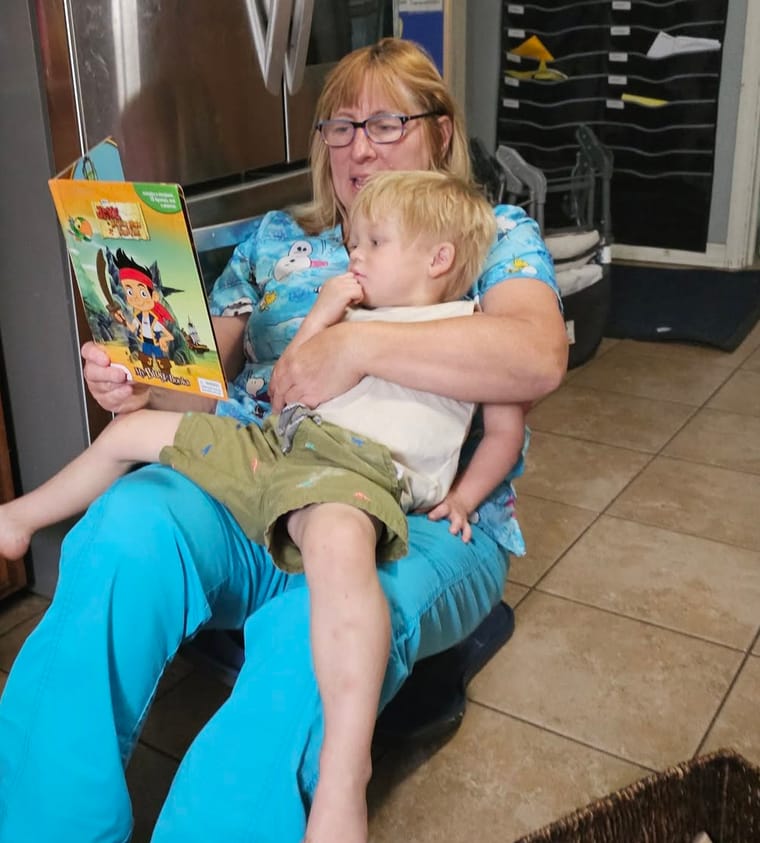 Michelle Mendoza reading a picture book to a young child on her lap in the home